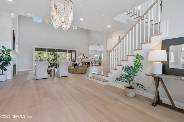 entryway with light hardwood / wood-style flooring, a large fireplace, a chandelier, and a high ceiling