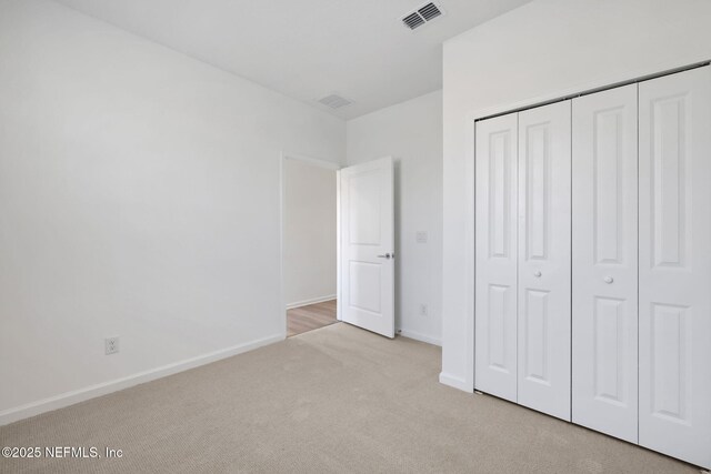 unfurnished bedroom with a closet and light carpet