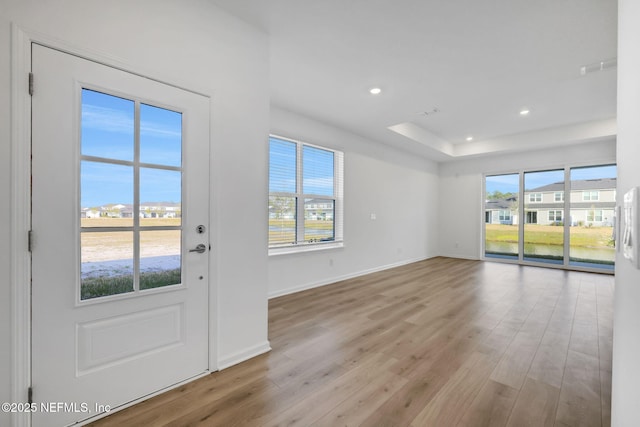 entrance foyer featuring a raised ceiling and light hardwood / wood-style flooring