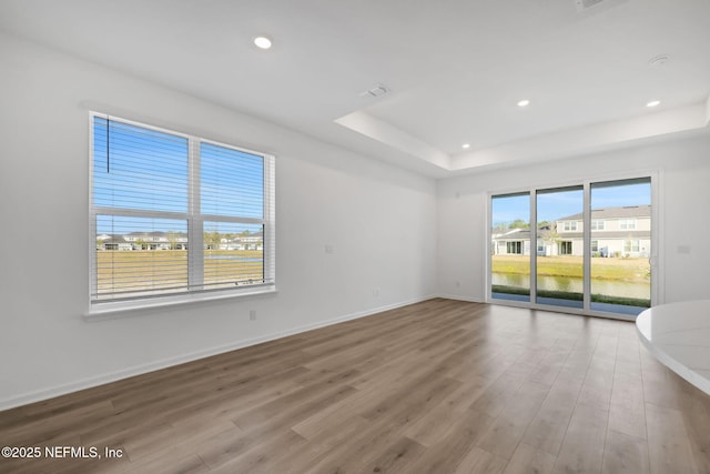 unfurnished room featuring a tray ceiling and light hardwood / wood-style flooring