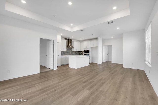 unfurnished living room featuring light hardwood / wood-style floors and a raised ceiling