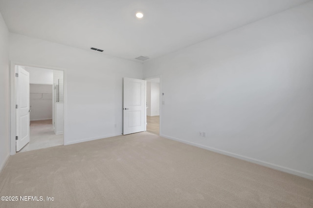 unfurnished bedroom featuring a spacious closet and light carpet