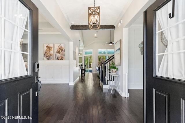 entryway featuring beamed ceiling, dark wood finished floors, stairs, and a decorative wall