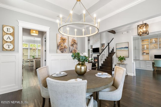 dining room featuring dark wood-type flooring, a notable chandelier, ornamental molding, and wainscoting