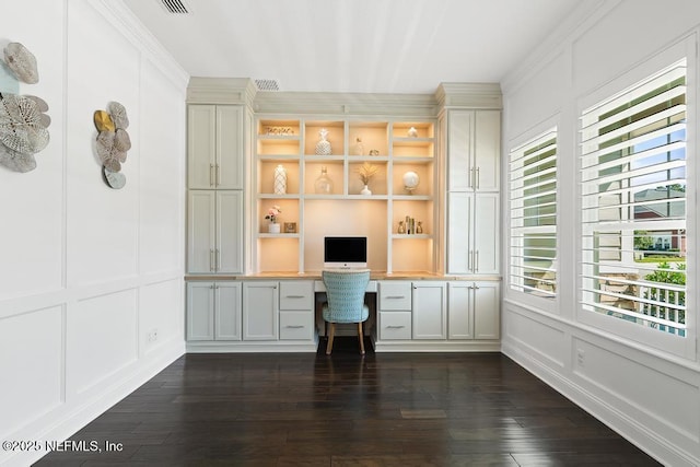 unfurnished office featuring dark wood finished floors, a decorative wall, and built in study area