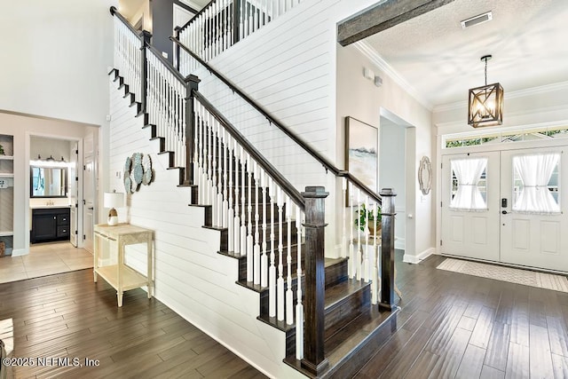 entryway featuring wood finished floors, visible vents, ornamental molding, stairs, and a textured ceiling