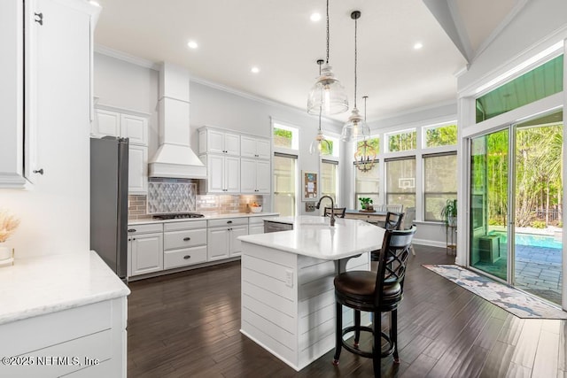 kitchen with premium range hood, a sink, stainless steel appliances, crown molding, and tasteful backsplash