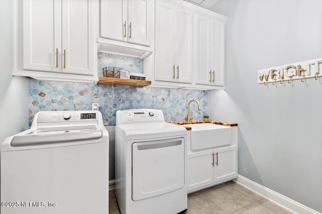 laundry area featuring washer and dryer, a sink, cabinet space, light tile patterned flooring, and baseboards