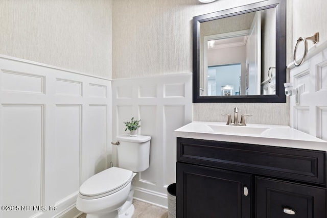 bathroom with wallpapered walls, a decorative wall, toilet, and a wainscoted wall