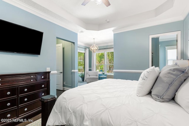 bedroom featuring crown molding, ceiling fan with notable chandelier, and a raised ceiling