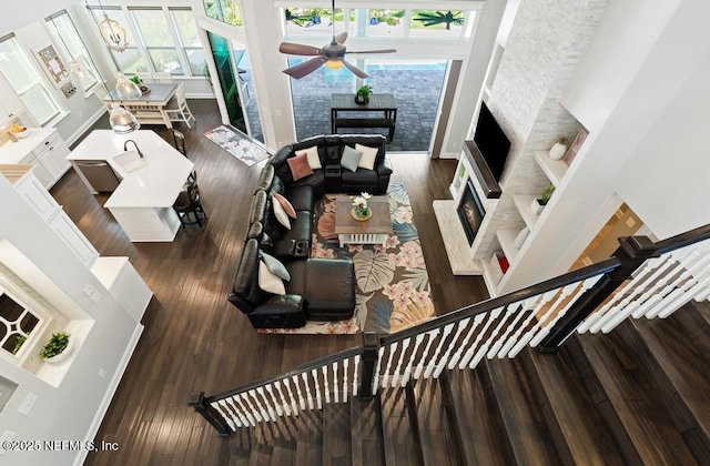 living room with a wealth of natural light, wood finished floors, a lit fireplace, and a towering ceiling