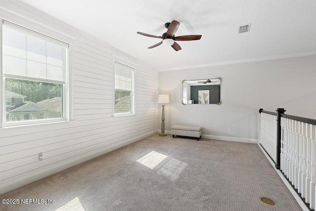 empty room featuring ornamental molding, carpet, visible vents, and ceiling fan