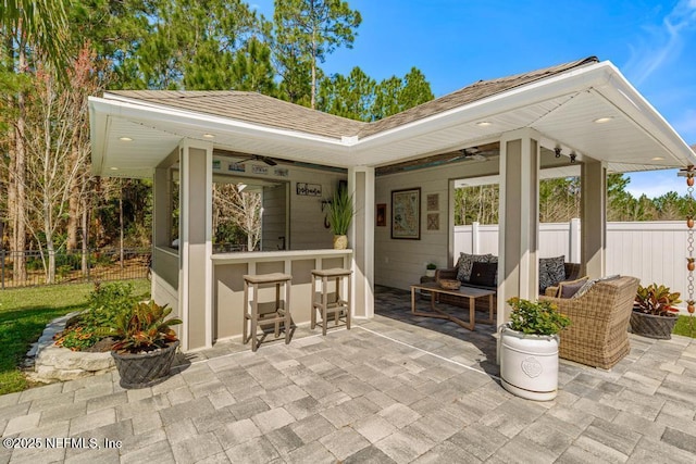 view of patio with outdoor dry bar, ceiling fan, and fence