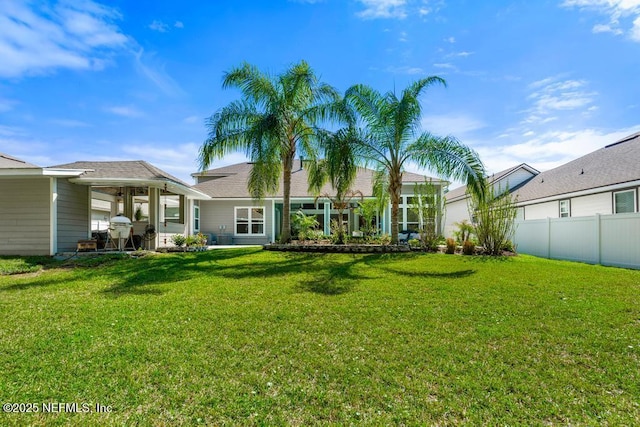 back of house with an attached garage, fence, and a lawn