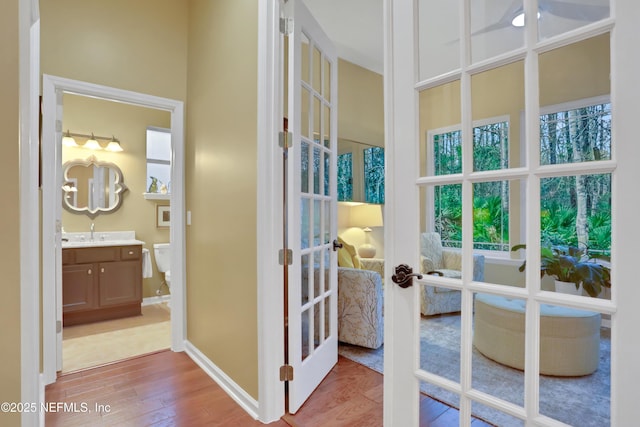 interior space with sink, light wood-type flooring, and french doors