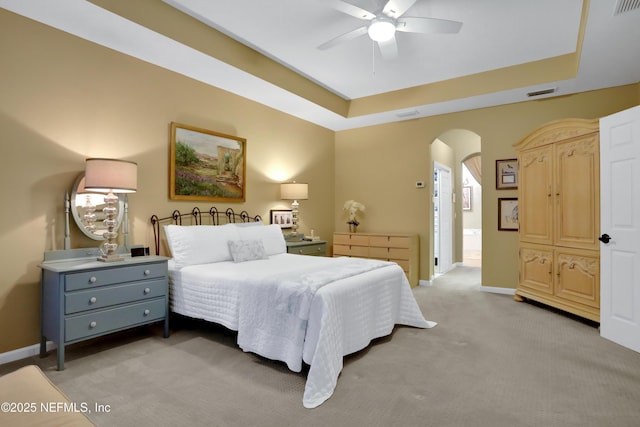 carpeted bedroom with connected bathroom, ceiling fan, and a raised ceiling