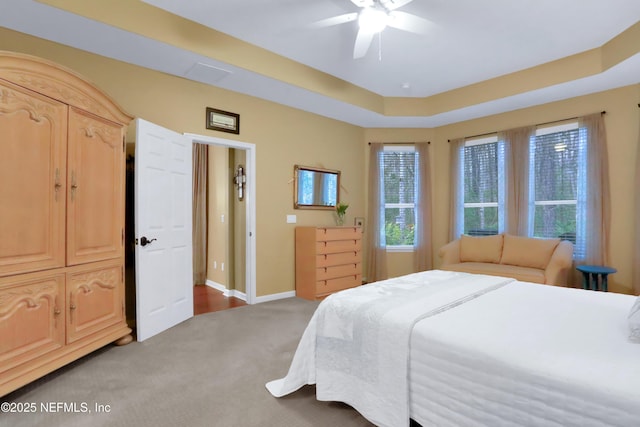 carpeted bedroom featuring a tray ceiling and ceiling fan