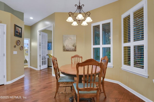 dining space with hardwood / wood-style floors and a chandelier