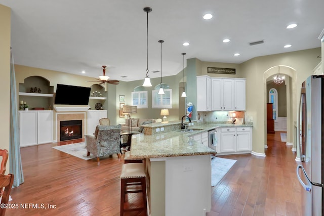 kitchen featuring appliances with stainless steel finishes, white cabinetry, sink, kitchen peninsula, and built in features