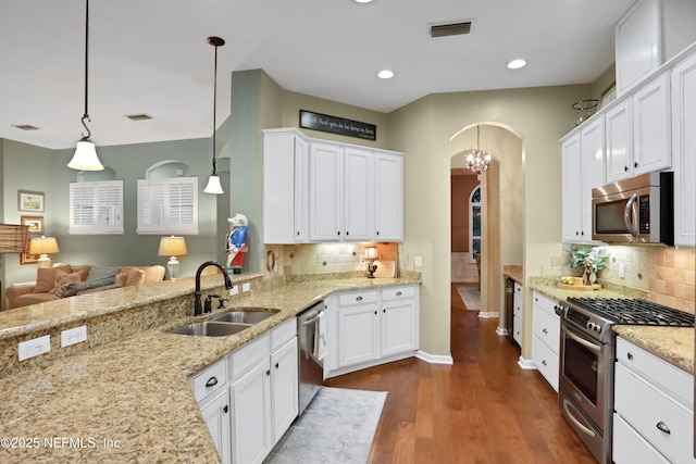 kitchen featuring pendant lighting, appliances with stainless steel finishes, sink, white cabinets, and tasteful backsplash