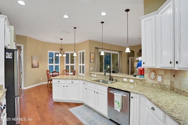 kitchen featuring sink, hanging light fixtures, appliances with stainless steel finishes, and kitchen peninsula