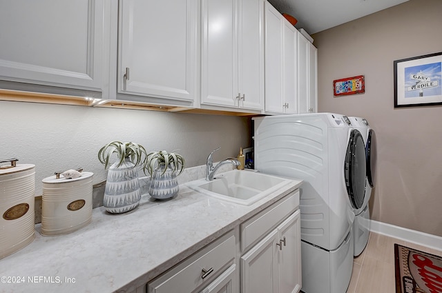 laundry room with sink, cabinets, washing machine and dryer, and light wood-type flooring