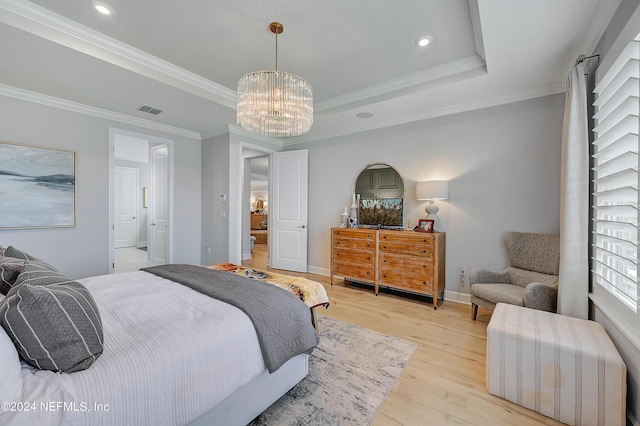 bedroom featuring crown molding, a chandelier, light hardwood / wood-style flooring, and a tray ceiling