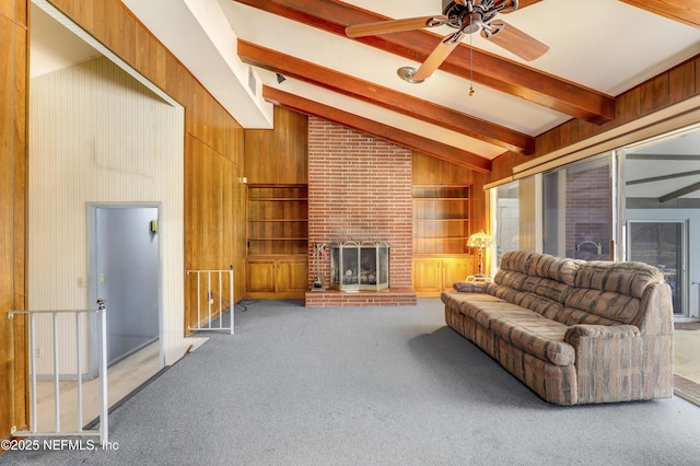 carpeted living room with vaulted ceiling with beams, ceiling fan, a brick fireplace, and wood walls