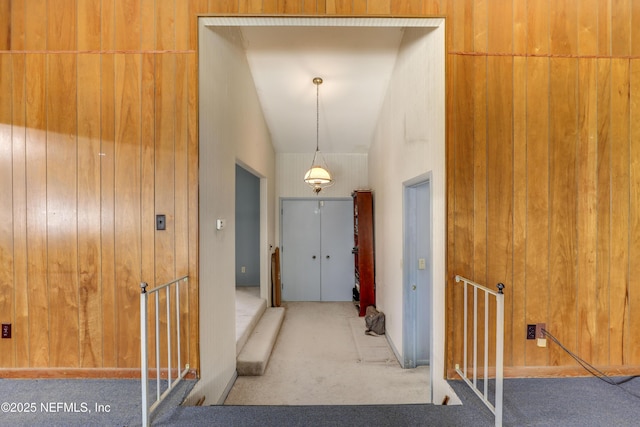 hall featuring carpet flooring and wood walls