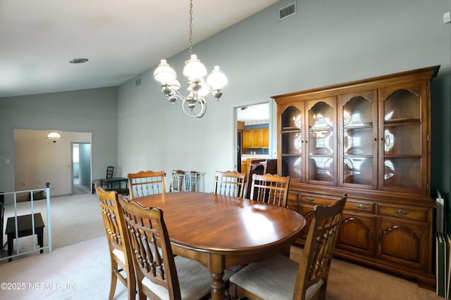 carpeted dining space with high vaulted ceiling and a chandelier