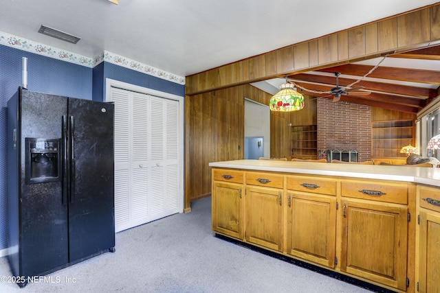 kitchen with ceiling fan, vaulted ceiling with beams, wooden walls, black refrigerator with ice dispenser, and light colored carpet