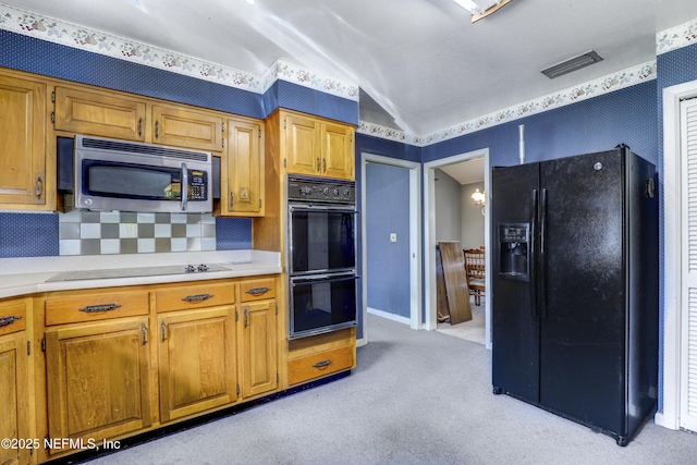 kitchen featuring tasteful backsplash, vaulted ceiling, light carpet, and black appliances