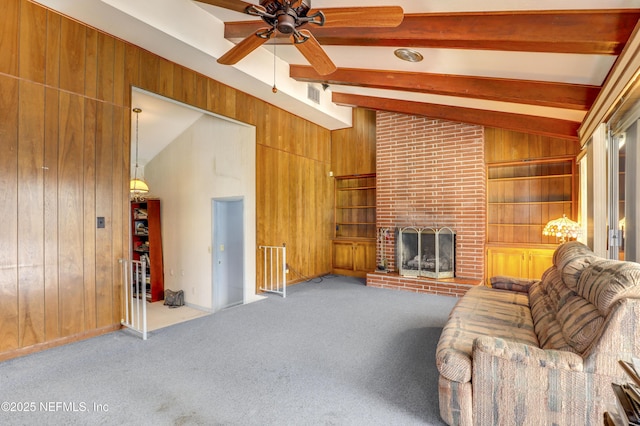 living room with vaulted ceiling with beams, a brick fireplace, wooden walls, carpet floors, and built in features