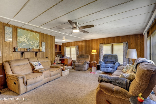 carpeted living room with ceiling fan and wood walls