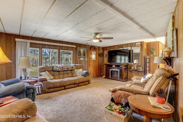 living room with ceiling fan, carpet flooring, and wood walls