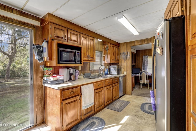 kitchen featuring appliances with stainless steel finishes, sink, and wood walls