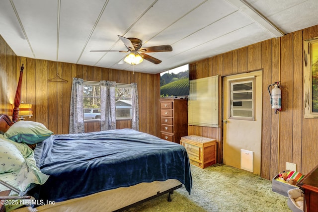 carpeted bedroom featuring ceiling fan and wooden walls