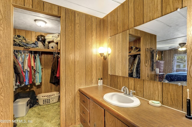 bathroom with ceiling fan, vanity, and wood walls