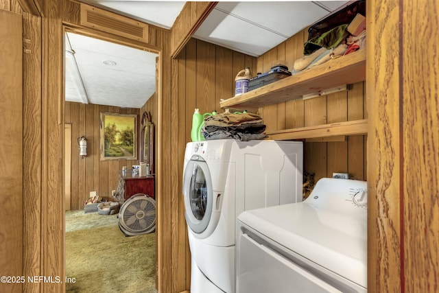 laundry area featuring carpet floors, washer and dryer, and wooden walls