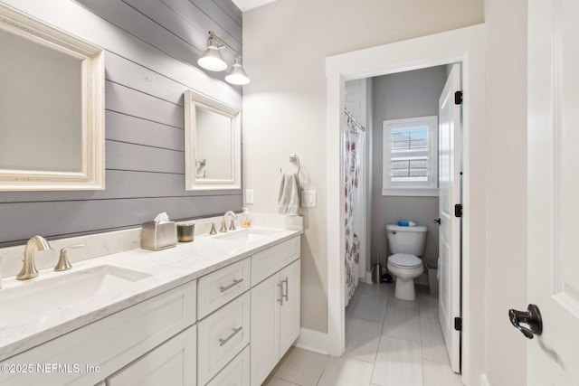 bathroom with vanity, toilet, tile patterned flooring, and wood walls