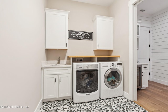 clothes washing area with cabinets, separate washer and dryer, sink, and light hardwood / wood-style flooring