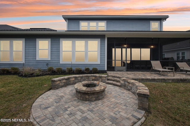 back house at dusk with a lawn, a patio area, and an outdoor fire pit