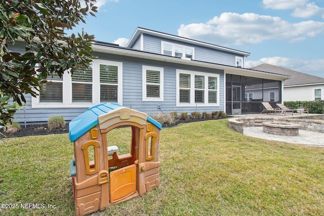 rear view of house featuring an outdoor fire pit, a playground, a sunroom, and a lawn