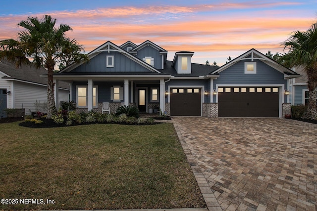 craftsman house with a porch, a garage, and a lawn