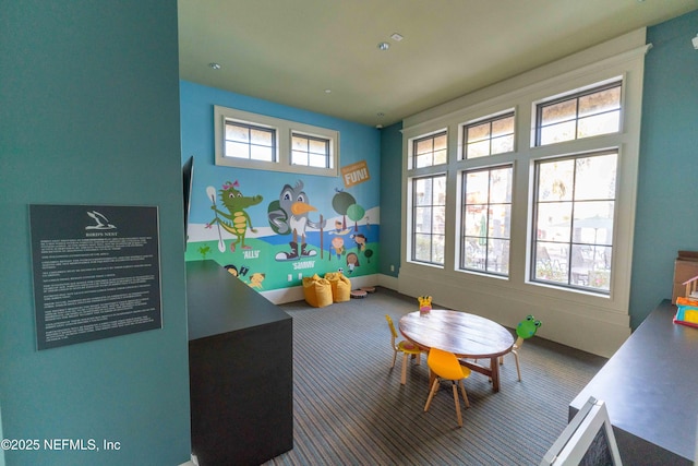 game room with a towering ceiling, a wealth of natural light, and carpet flooring