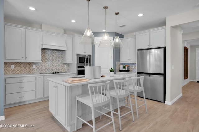 kitchen with white cabinets, decorative light fixtures, a center island, and appliances with stainless steel finishes