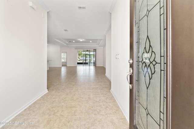 entryway with light tile patterned floors and a tray ceiling