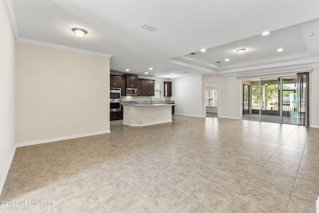 unfurnished living room with a raised ceiling, crown molding, and light tile patterned floors