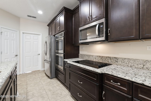 kitchen featuring dark brown cabinetry, light stone countertops, stainless steel appliances, and a textured ceiling