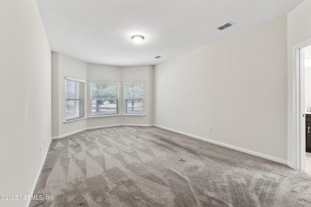 carpeted empty room featuring a textured ceiling